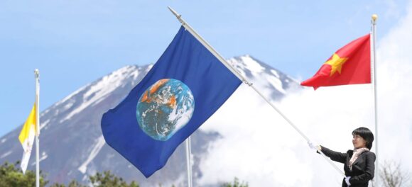 The Earth flag is presented on stage at Fuji Sanctuary, with Mount Fuji in the background.